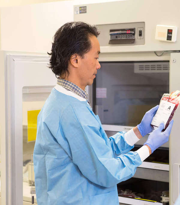 Technician with blood bank refrigerator